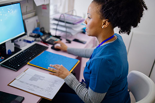 Nurse Informaticist sits behind computer