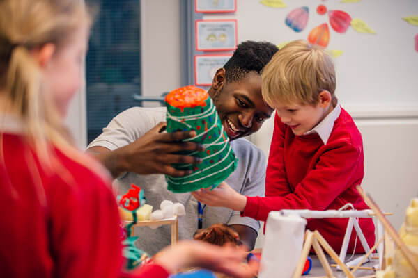 Teacher helps young boy with craft