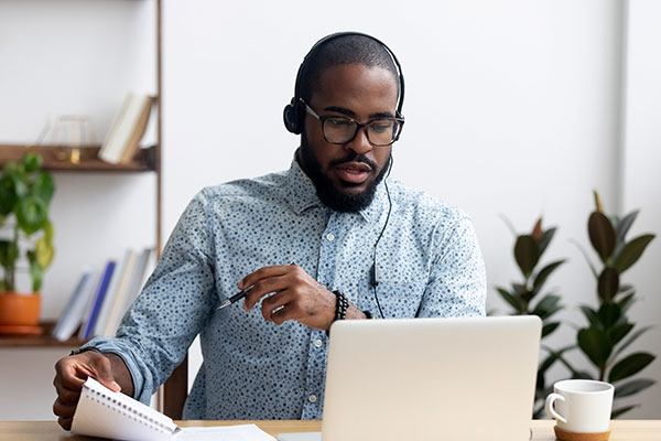 Student watching an online info session, taking notes