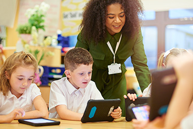 Teacher supervising children using tablet devies