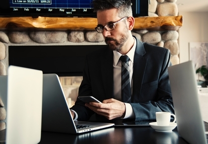 A person in a suit using a phone and laptop