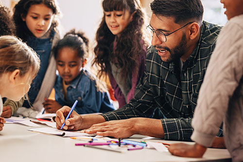 Teacher drawing at a table surrounded by students
