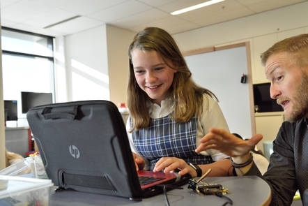 Social work professional sitting with a child as they use a laptop